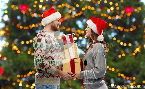 Image of happy couple in christmas sweaters with gifts