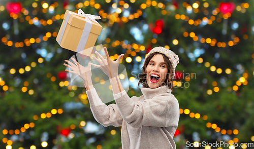 Image of young woman in winter hat catching gift box