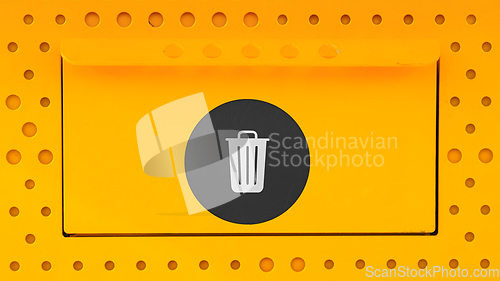 Image of Yellow trash can close-up with a black sticker