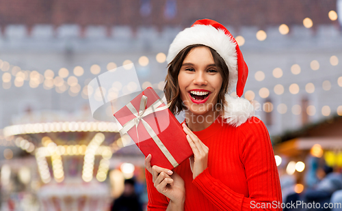 Image of happy young woman in santa hat with red gift box