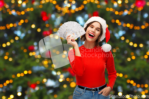 Image of happy woman in santa hat with money on christmas