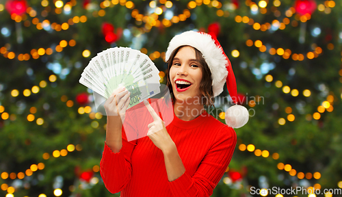 Image of happy woman in santa hat with money on christmas