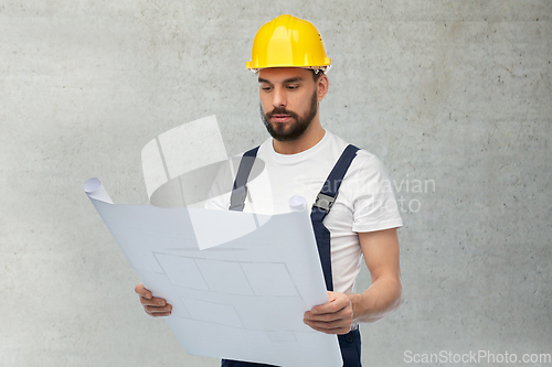 Image of male worker or builder in helmet with blueprint