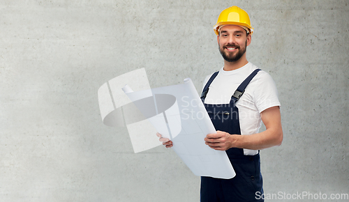 Image of male worker or builder in helmet with blueprint