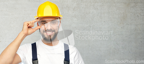 Image of happy male worker or builder in helmet and overall