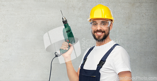 Image of happy male worker or builder in helmet with drill