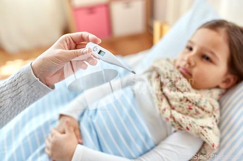 Image of mother measuring temperature of sick daughter