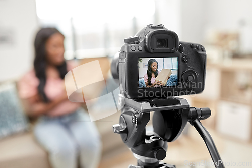 Image of female video blogger with camera and box at home