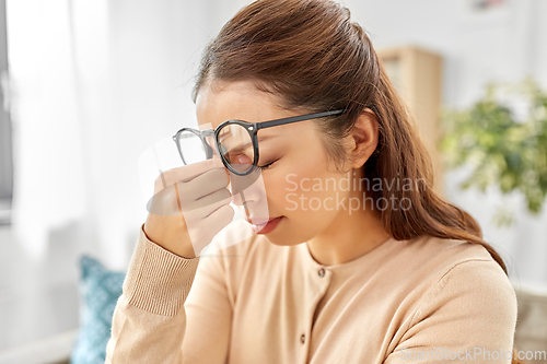 Image of tired asian woman with glasses rubbing nose bridge