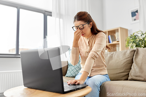 Image of tired woman with laptop working at home office