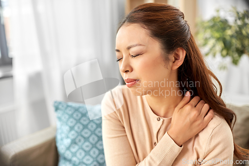 Image of asian woman suffering from ache in neck at home