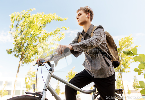 Image of teenage boy with earphones and bag riding bicycle