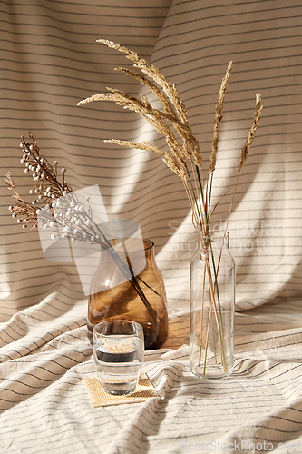 Image of glass of water, decorative dried flowers in vases