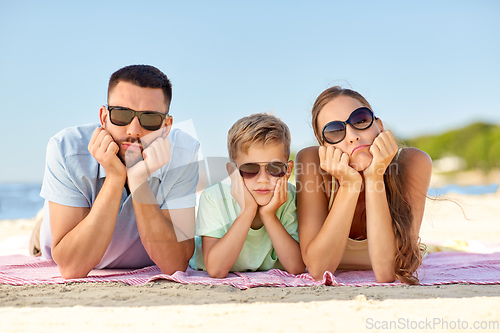 Image of unhappy family lying on summer beach