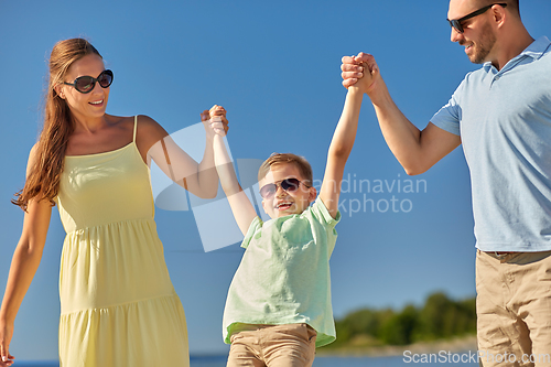 Image of happy family walking along summer beach