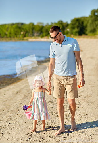 Image of happy father walking with little daughter on beach