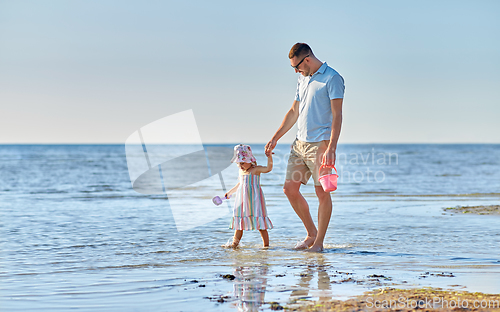 Image of happy father walking with little daughter on beach