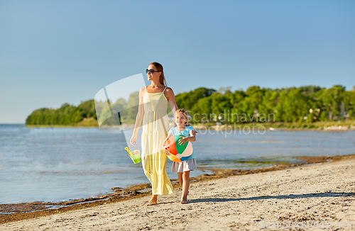 Image of mother and daughter with ball walking along beach