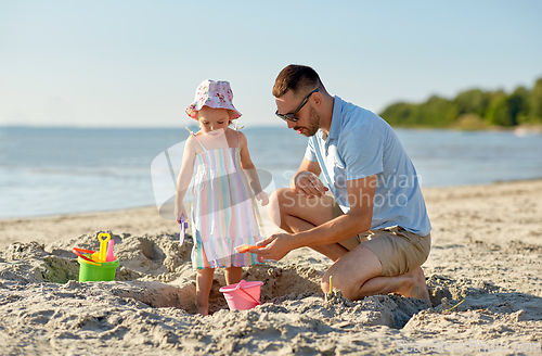 Image of father and daughter playing with toys on beach