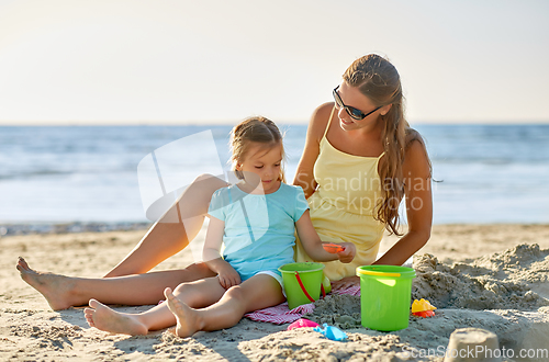 Image of mother and daughter playing with toys on beach