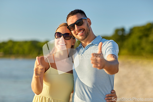 Image of happy couple showing thumbs up on summer beach