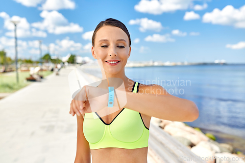 Image of smiling young woman with fitness tracker outdoors