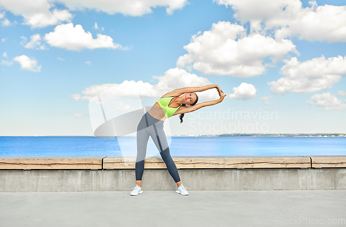 Image of young woman doing sports and stretching outdoors