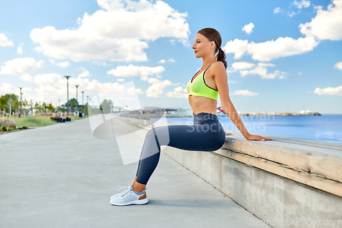 Image of happy young woman doing sports on sea promenade