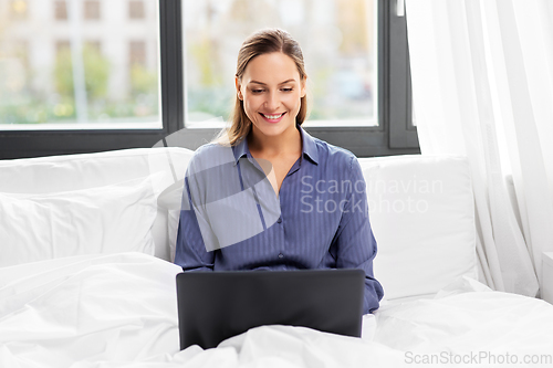 Image of young woman with laptop in bed at home bedroom