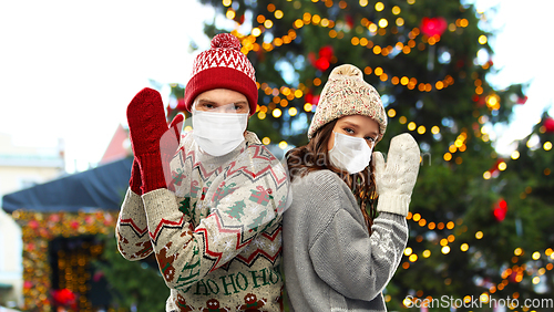 Image of couple in protective masks and christmas sweaters