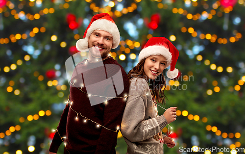 Image of happy couple in christmas sweaters and santa hats