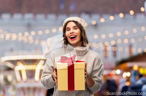 Image of happy young woman in hat holding chrismas gift