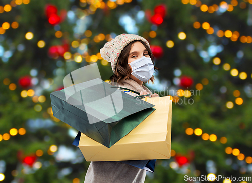 Image of woman in face mask with shopping bags on christmas