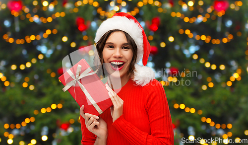 Image of happy young woman in santa hat with red gift box