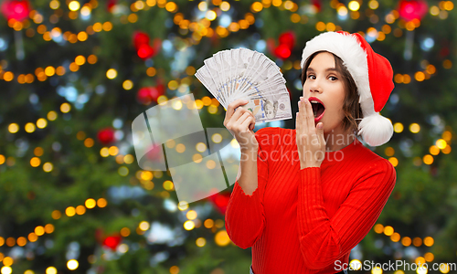 Image of surprised woman in santa hat with money