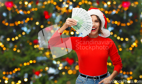 Image of happy woman in santa hat with money on christmas