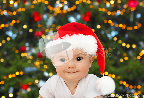 Image of baby in santa hat over christmas tree lights