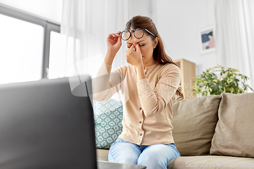 Image of tired woman with laptop working at home office