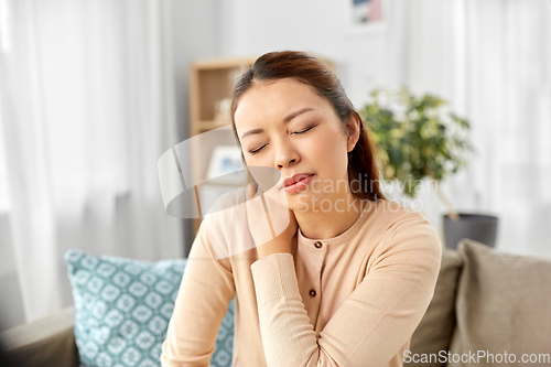 Image of asian woman suffering from ache in neck at home