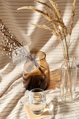 Image of glass of water, decorative dried flowers in vases