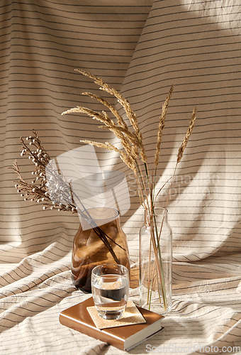 Image of glass of water, decorative dried flowers in vases