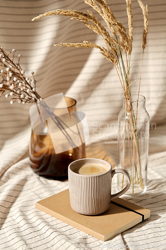 Image of cup of coffee, diary and dried flowers in vases