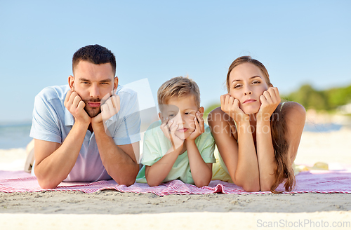 Image of unhappy family lying on summer beach