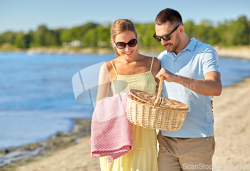 Image of happy couple with picnic basket on summer beach