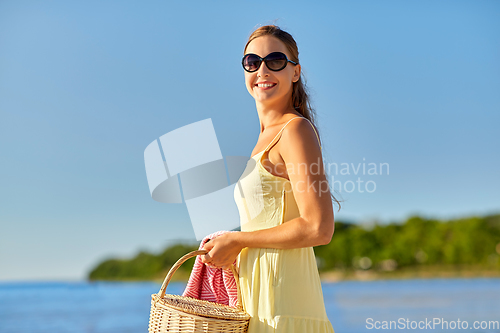 Image of happy woman with picnic basket on summer beach