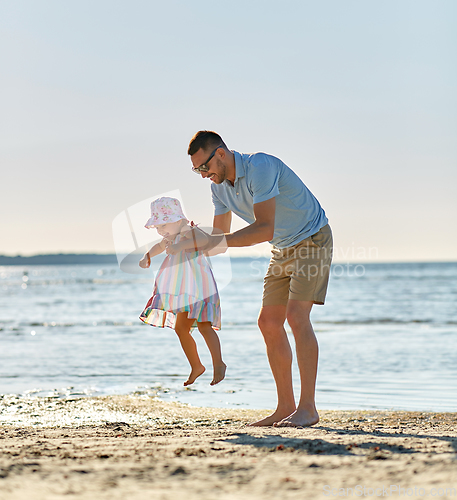 Image of happy father playing with little daughter on beach