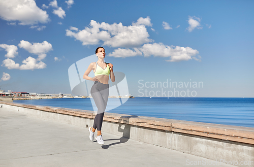 Image of young woman running along sea promenade