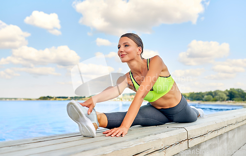 Image of young woman doing full split at seaside