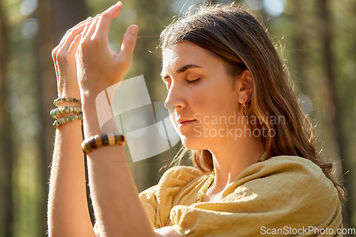 Image of woman or witch performing magic ritual in forest