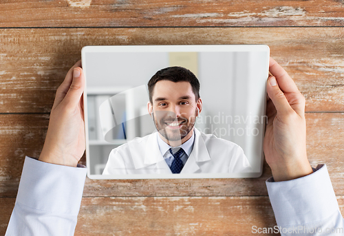 Image of hands of holding tablet pc with doctor on screen